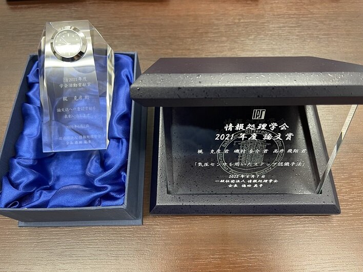 2021年度論文賞の盾(右)と2021年度学会活動貢献賞の賞牌