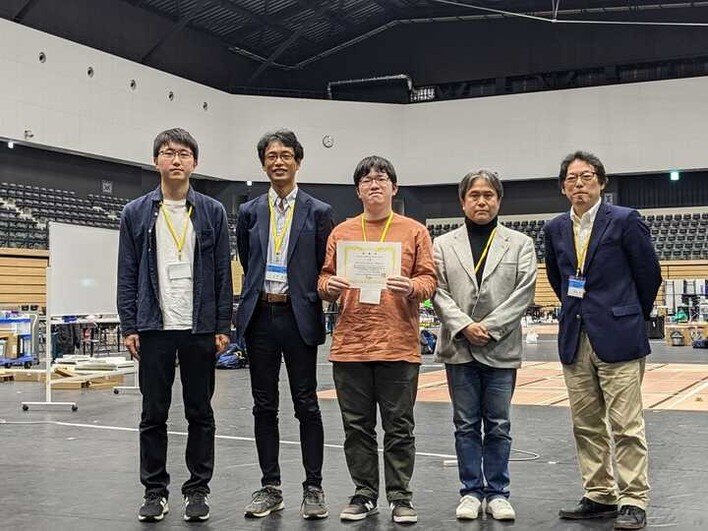 授賞式のAIT-Rescue (左から鈴木宏哉さん、岩田員典愛知大学教授、上原温揮さん、伊藤暢浩教授、岡田浩之ロボカップ日本委員会会長)